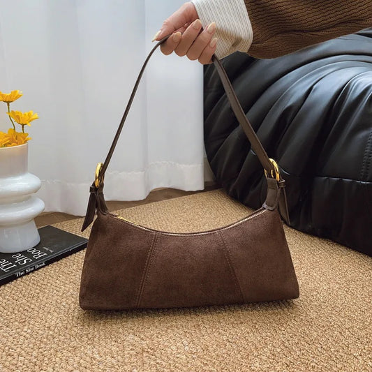 Brown Suede handbag held by a person with a blurred background